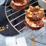 S'Mores mini donuts on a cooling rack with marshmallows and crack cracker crumbs on the counter top background.