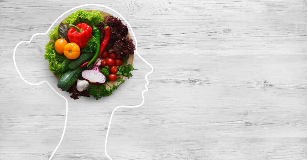 A graphic of fresh vegetables in a drawing of a woman's head symbolizing health nutrition.